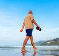 old man walking on beach