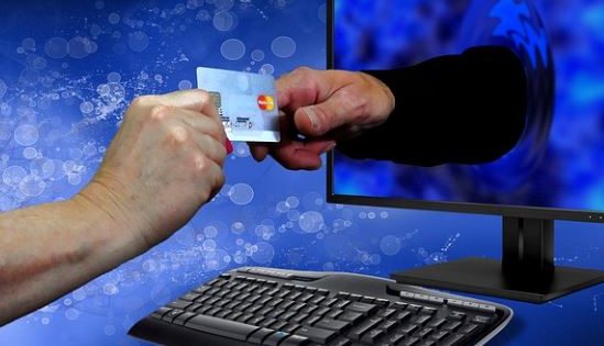 hand offering credit card through monitor